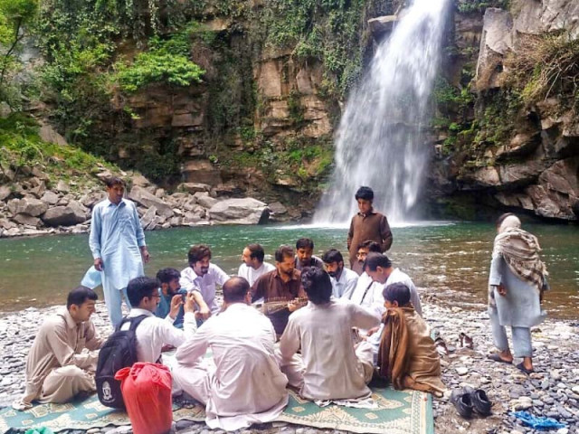 a group of people enjoy a musical performance near shingrai waterfall photo express a group of people enjoy a musical performance near shingrai waterfall photo express