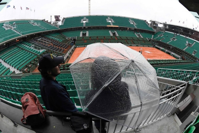 a person stands under an umbrella in the empty stands of the philippe chatrier court as play is suspended due to rain at the roland garros 2016 french tennis open in paris on may 30 2016 photo afp a person stands under an umbrella in the empty stands of the philippe chatrier court as play is suspended due to rain at the roland garros 2016 french tennis open in paris on may 30 2016 photo afp
