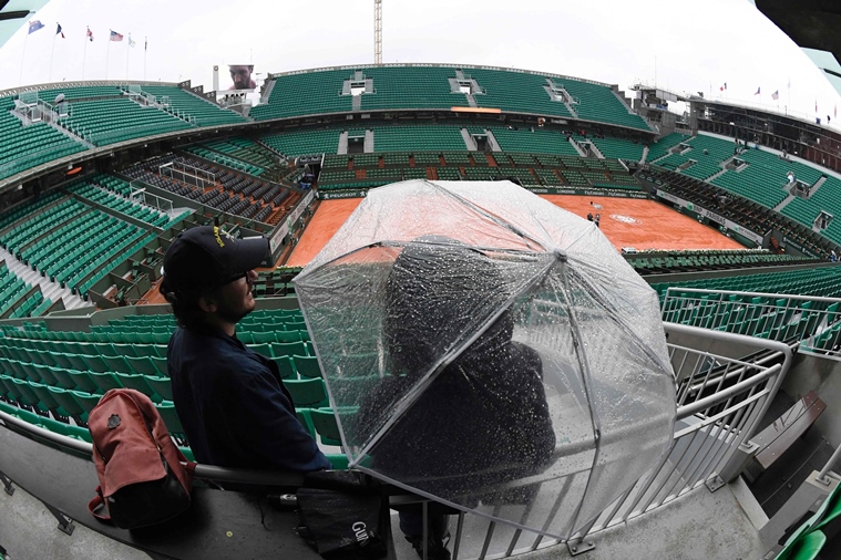 a person stands under an umbrella in the empty stands of the philippe chatrier court as play is suspended due to rain at the roland garros 2016 french tennis open in paris on may 30 2016 photo afp