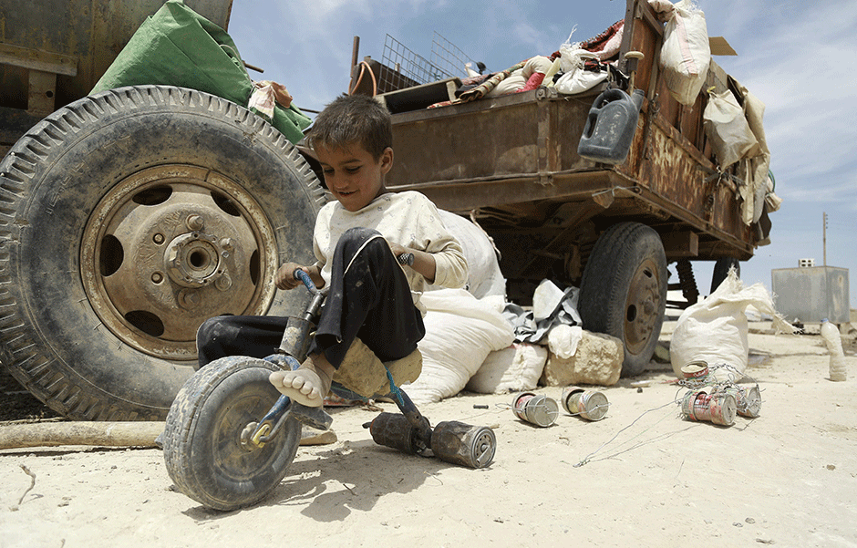 an iraqi child who fled with his family the northern province of nineveh following the advance of militants of the islamic state is group plays with a makeshift tricycle in a refugee camp in al hawl located some 14 kilometers from the iraqi border in syria s northeastern hassakeh province on may 31 2016 the camp houses some 5000 refugees according to its chief ciwan sidou afp photo delil souleiman photo afp