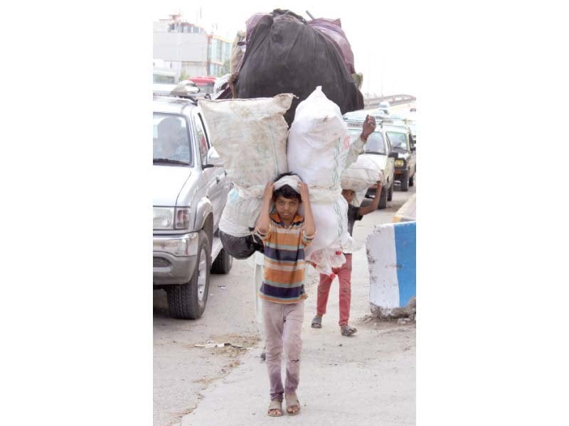 a boy carrying a heavy bag of empty plastic bottles on his head walks on jinnah avenue on thursday photo muhammad javaid express