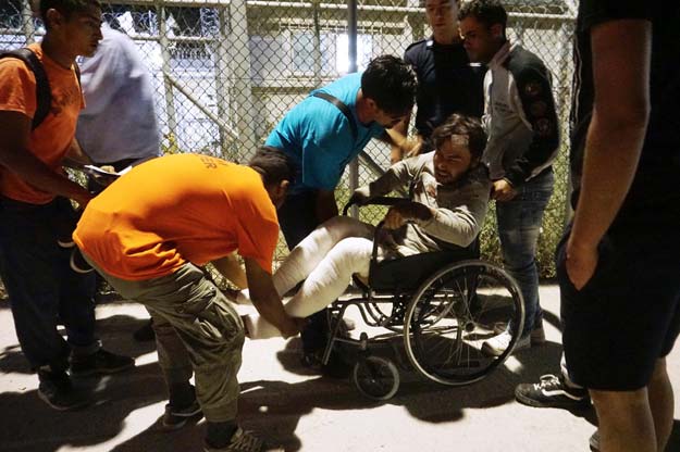 volunteers help an injured migrant following overnight clashes between migrants at the moria migrant detention camp on the island of lesbos early on june 2 2016 photo afp