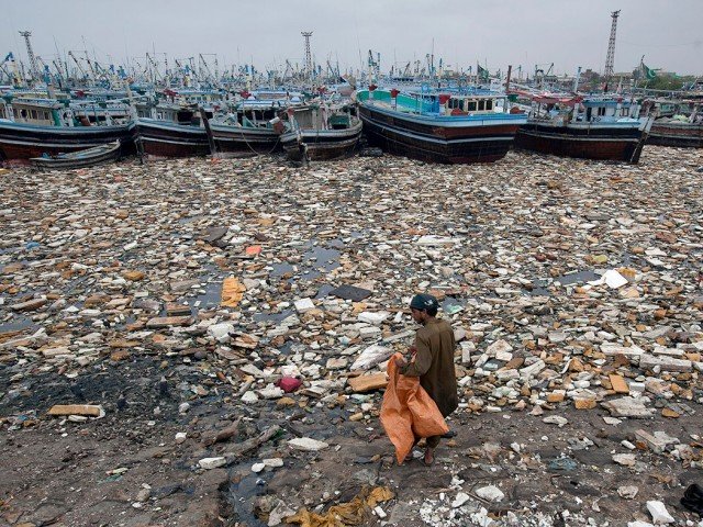 a boy looks for recyclable items in the polluted waters of karachi harbour pakistan photo reuters file