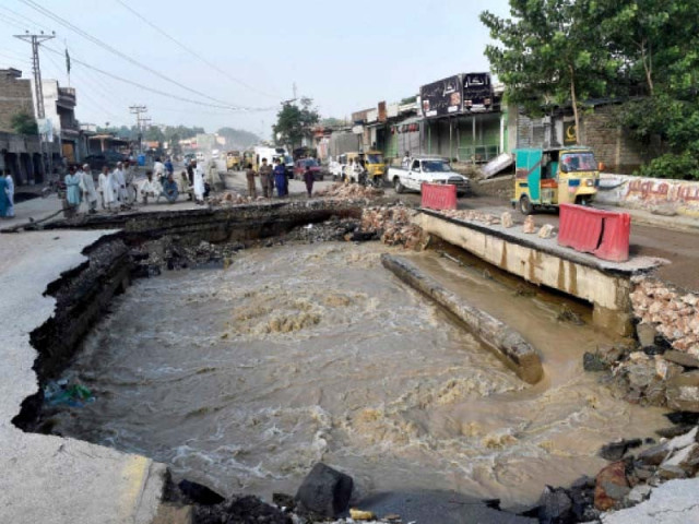 residents gather beside a road damaged by floodwaters following heavy downpours photo afp residents gather beside a road damaged by floodwaters following heavy downpours photo afp