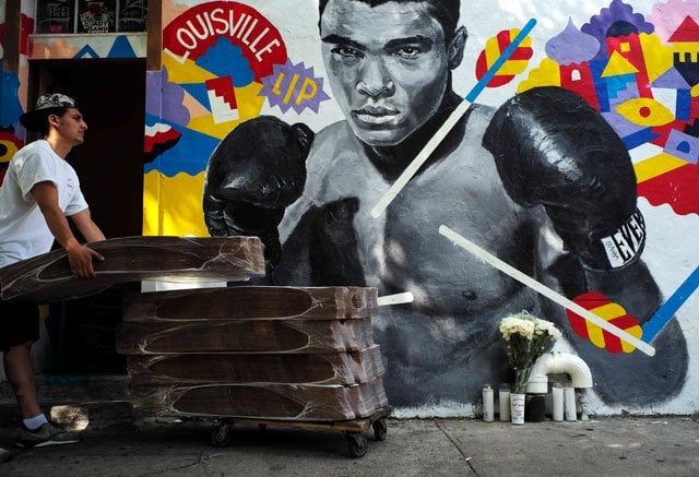 a man loads pizza boxes next to a mural of boxer muhammad ali in new york on june 4 2016 ali the three time world heavyweight champion and colorful civil rights activist whose fame transcended the world of sports and made him an iconic figure of the 20th century died on june 3 at age of 74 after a long battle with parkinson 039 s disease photo afp