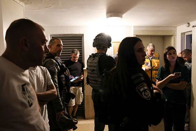 Israeli security personnel and members of the media take shelter as a siren sounds while rockets are launched from the Gaza Strip, in Mevaseret Zion, Israel October 7, 2023 (Reuters)