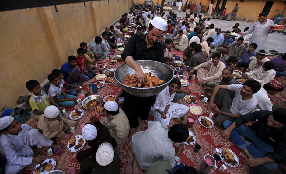 a volunteer carries food trays for others before breaking fast at memon mosque in karachi photo reuters