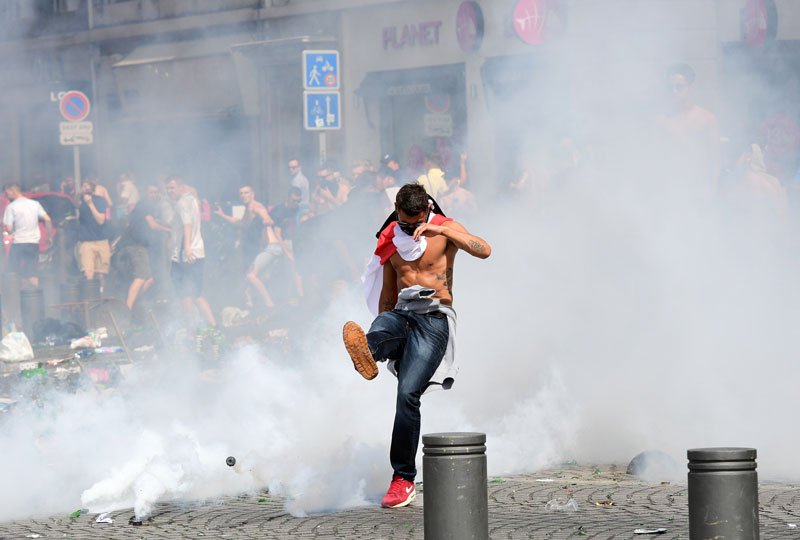 an england fan kicks away a tear gas canister after tear gas was released by french police in the city of marseille southern france on june 11 2016 ahead of the euro 2016 football match between england and russia photo afp