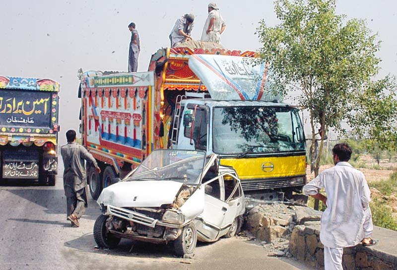 people look at the car that was crushed by a speeding dumper truck near islamabad photo waseem nazir express