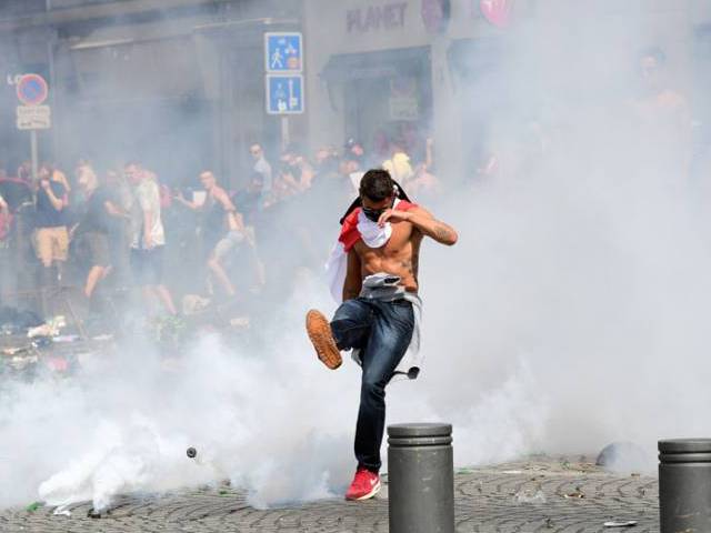 an england fan kicks away a tear gas canister after tear gas was released by french police in marseille on june 11 2016 photo afp