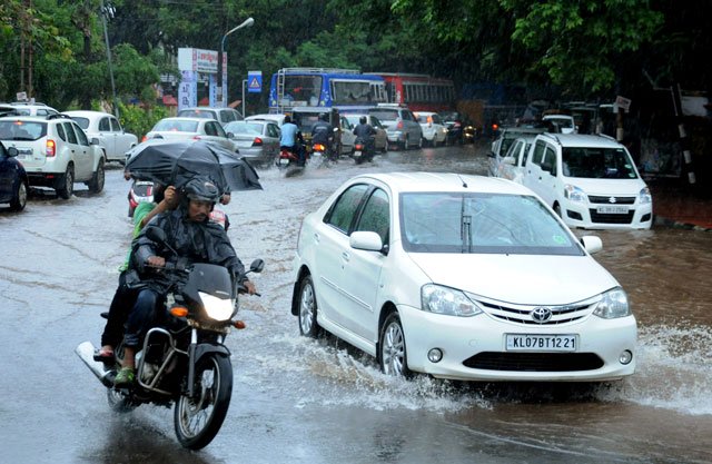 this file photograph taken on june 8 2016 shows indian commuters as they make their way along a waterlogged road during heavy monsoon rains in kochi photo afp file