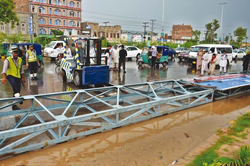 traffic policemen try to remove a billboard that fell due to heavy rainfall in the city photos muhammad iqbal express