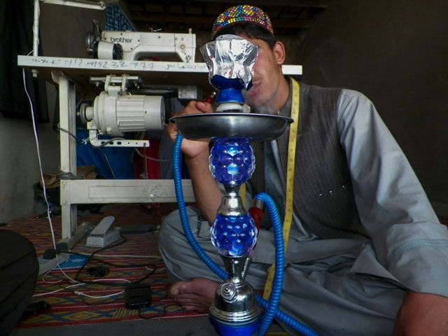 this photograph taken on april 27 2016 shows najeebullah 18 who survived a taliban insider attack carried out by a bacha or child sex slave smoking a shisha in tarin kot photo afp