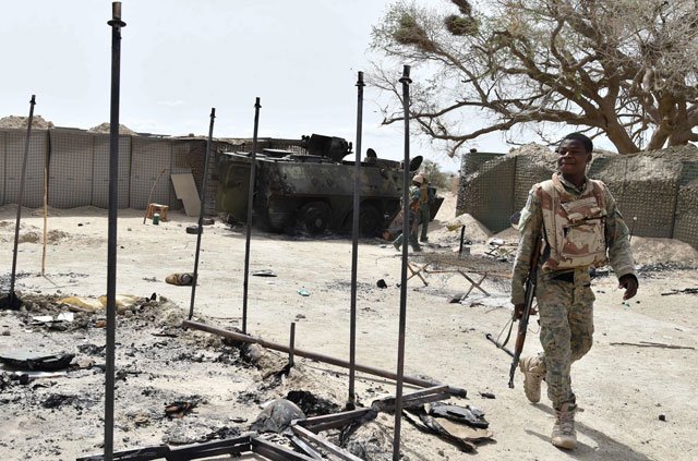 a soldier walks past a damaged army personnel carrier on june 17 2016 in the military camp in bosso photo afp