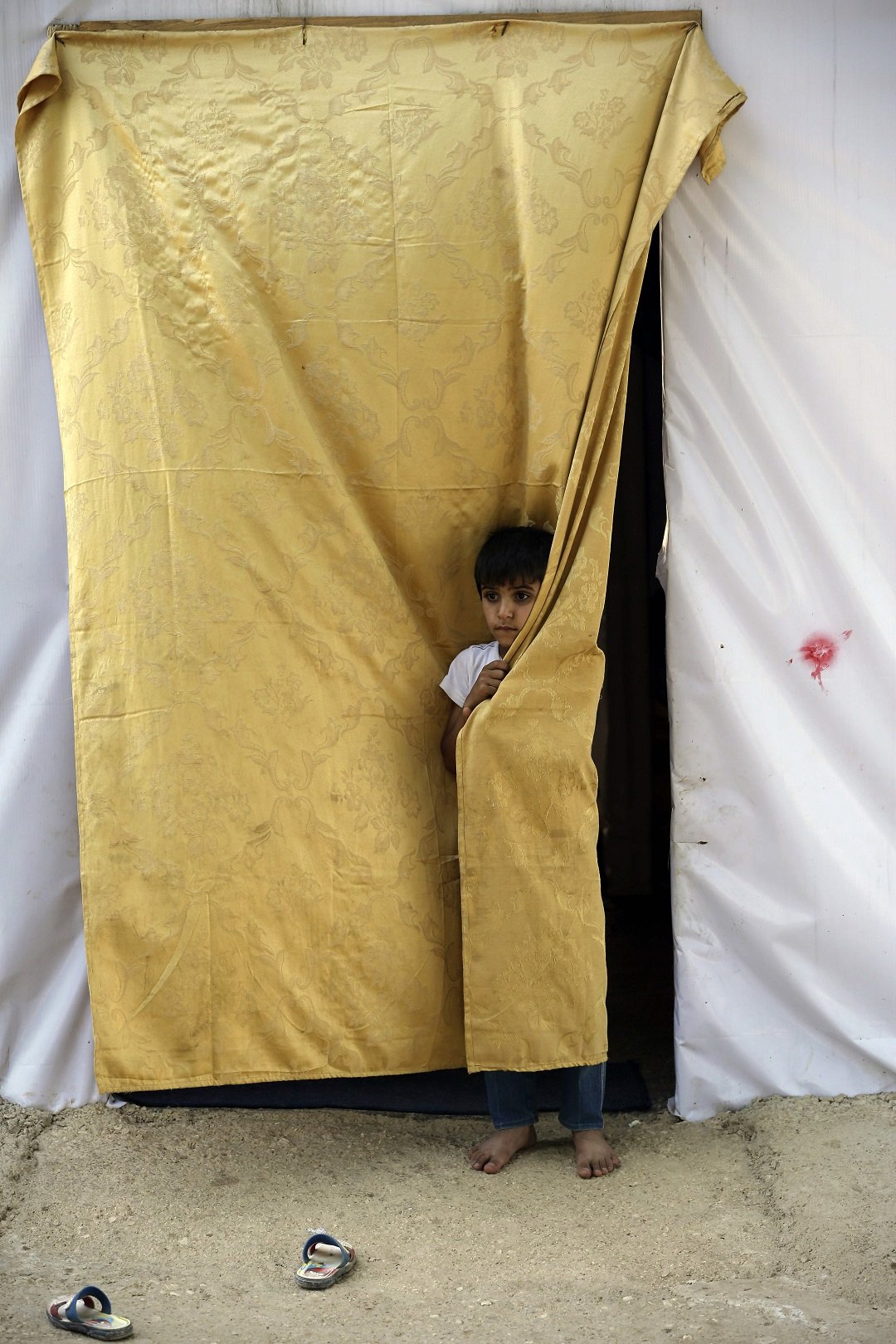 a syrian refugee child stands at the entrance of his tent at an unofficial camp for refugees photo afp