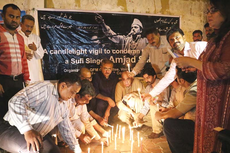 javed qazi qurrat mirza and other participants light candles on a footpath outside karachi press club on thursday photo express