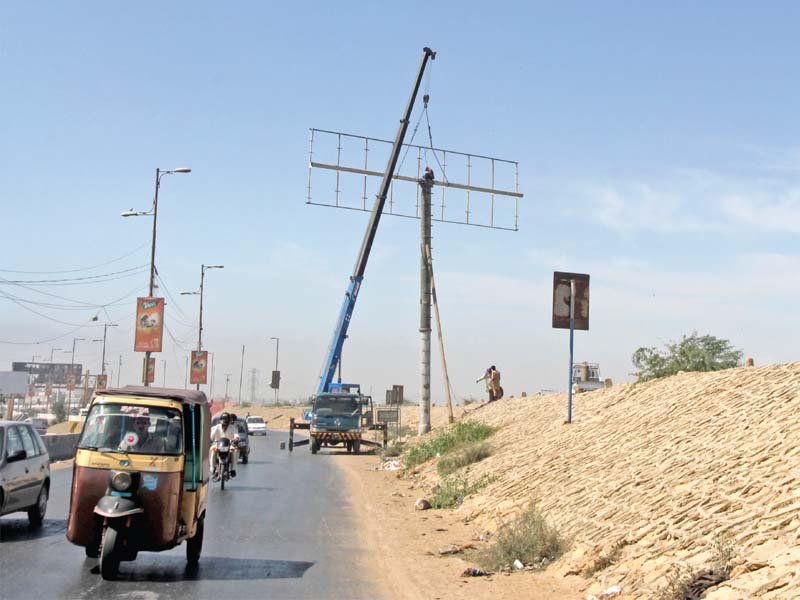 a worker removes a billboard frame from a tall iron pole erected at shaheed e millat expressway on saturday photo athar khan express