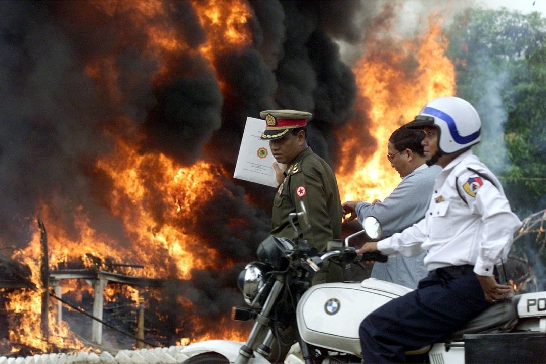 a policeman rides past officials as a huge fire engulfs illicit drugs at a destruction ceremony conducted by myanmar 039 s government in yangon photo reuters