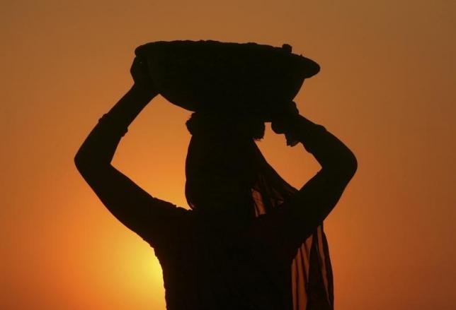 a woman labourer carrying cement is silhouetted against the setting sun at the site of a commercial complex on the outskirts of jammu november 22 2012 photo reuters