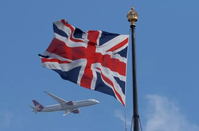 a virgin atlantic passenger jet flies past the union flag above the houses of parliament in westminster in central london britain photo reuters
