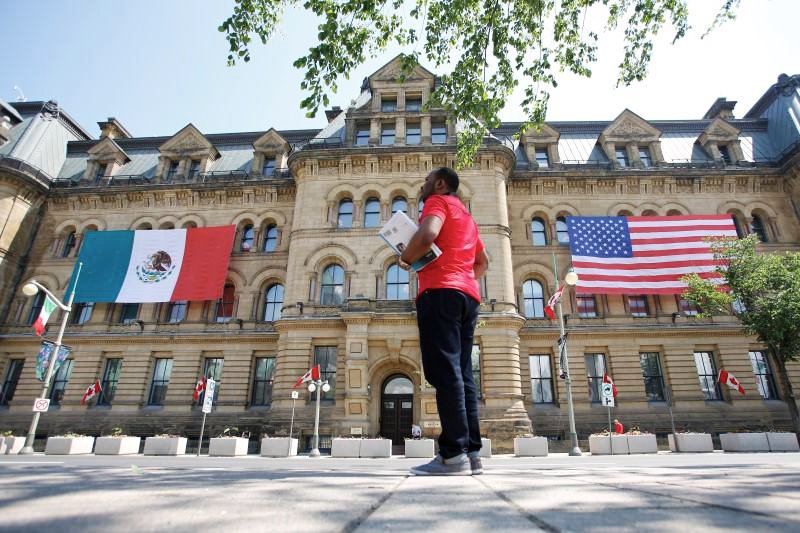 the mexican and us flags hang from the langevin block in advance of wednesday 039 s north american leaders 039 summit as a man waits for a bus by in ottawa ontario canada june 27 2016 photo reuters