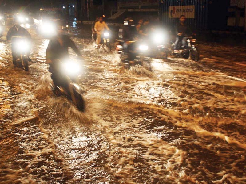 motorcyclists drive through rainwater accumulated on ma jinnah road photo online