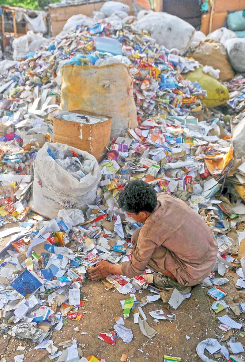 a young boy rummages through trash to make a living photo file