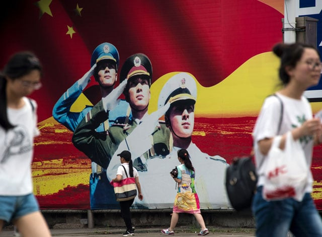 pedestrians pass a military propaganda poster on a street in shanghai on july 12 2016 photo afp pedestrians pass a military propaganda poster on a street in shanghai on july 12 2016 photo afp