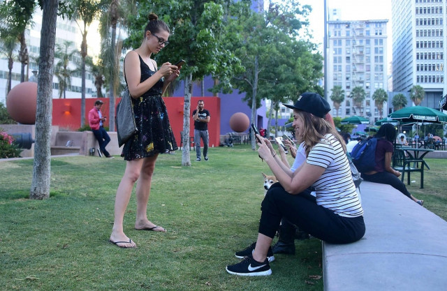 people look at their cellphones while playing pokemon go at pershing square in los angeles california photo afp people look at their cellphones while playing pokemon go at pershing square in los angeles california photo afp