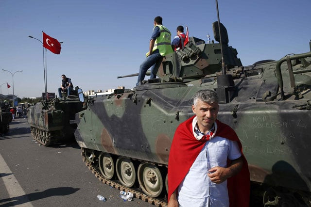 a man wrapped in a turkish flag stands next to military vehicles in front of sabiha airport in istanbul turkey july 16 2016 photo reuters