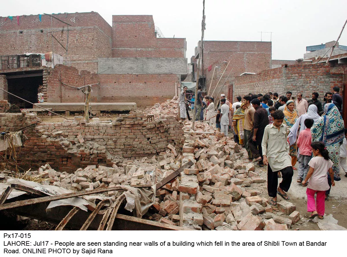 people are seen standing near walls of a building which fell in the area of shibli town of lahore on sunday photo online people are seen standing near walls of a building which fell in the area of shibli town of lahore on sunday photo online