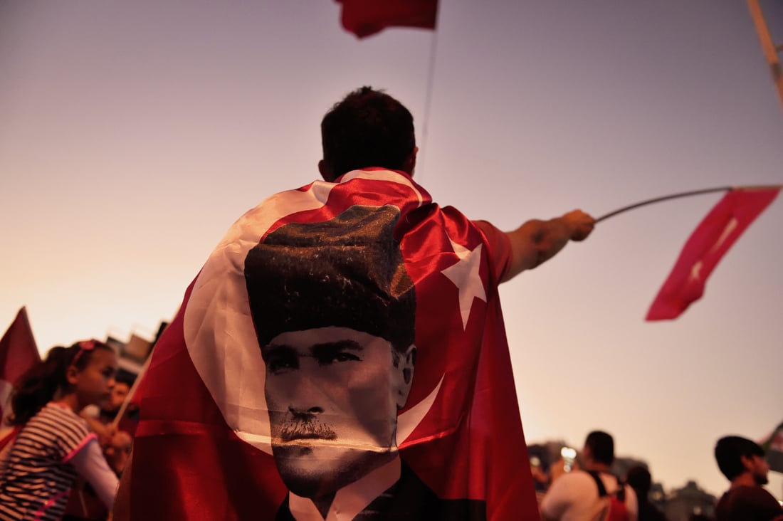 a boy is wrapped in a flag of the founder of modern turkey mustafa kemal ataturk on taksim square on july 17 2016 following a failed coup attempt photo afp