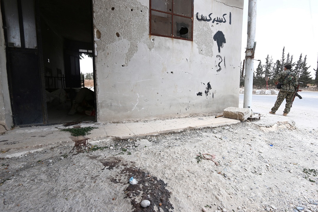 a fighter from the syria democratic forces sdf stands near the entrance to a room with a dead islamic state fighter on the ground photo reuters