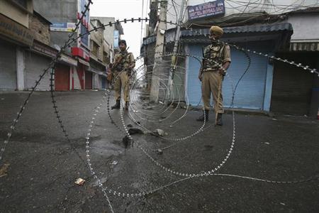 policemen stand guard at a street during a curfew following riots in indian held kashmir photo reuters