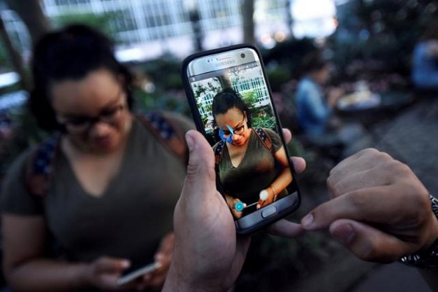 a pokemon appears on the screen next to a woman as a man plays the augmented reality mobile game quot pokemon go quot by nintendo photo reuters