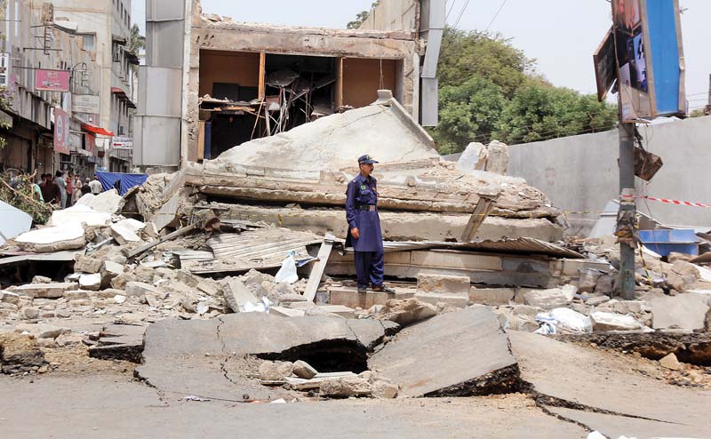 a watchman stands over the ruins of mobile street mall in saddar which collapsed on wednesday morning allegedly due to a gas explosion photo athar khan express