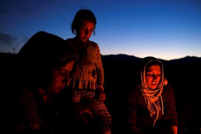 a girl watches as women prepare dinner at a makeshift camp for refugees and migrants at the greek macedonian border near the village of idomeni greece may 13 2016 photo reuters