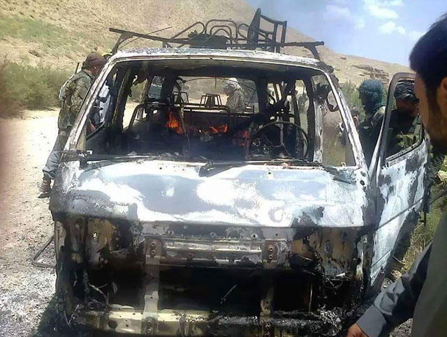 afghan security forces inspect a burnt out vehicle believed to have transported foreign tourists who came under attack from taliban militants in western herat province on august 5 2016 photo afp