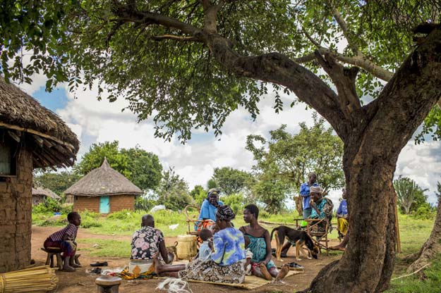 mugosi isombe seated on mat in blue and paulina mukosa seated on mat in teal eat lunch with family and other friends photo charlie shoemaker