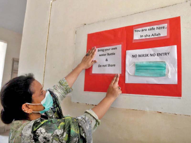 a teacher puts up guidelines for preventing the spread of coronavirus among students on a notice board at a government school in north nazimabad a day before classes are set to resume photo app