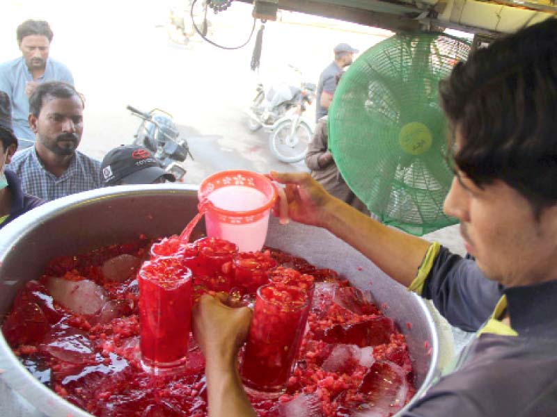 a vendor pours out watermelon juice for parched customers at a roadside stall in karachi as soaring temperatures left citi zens searching for ways for beat the heat photo online