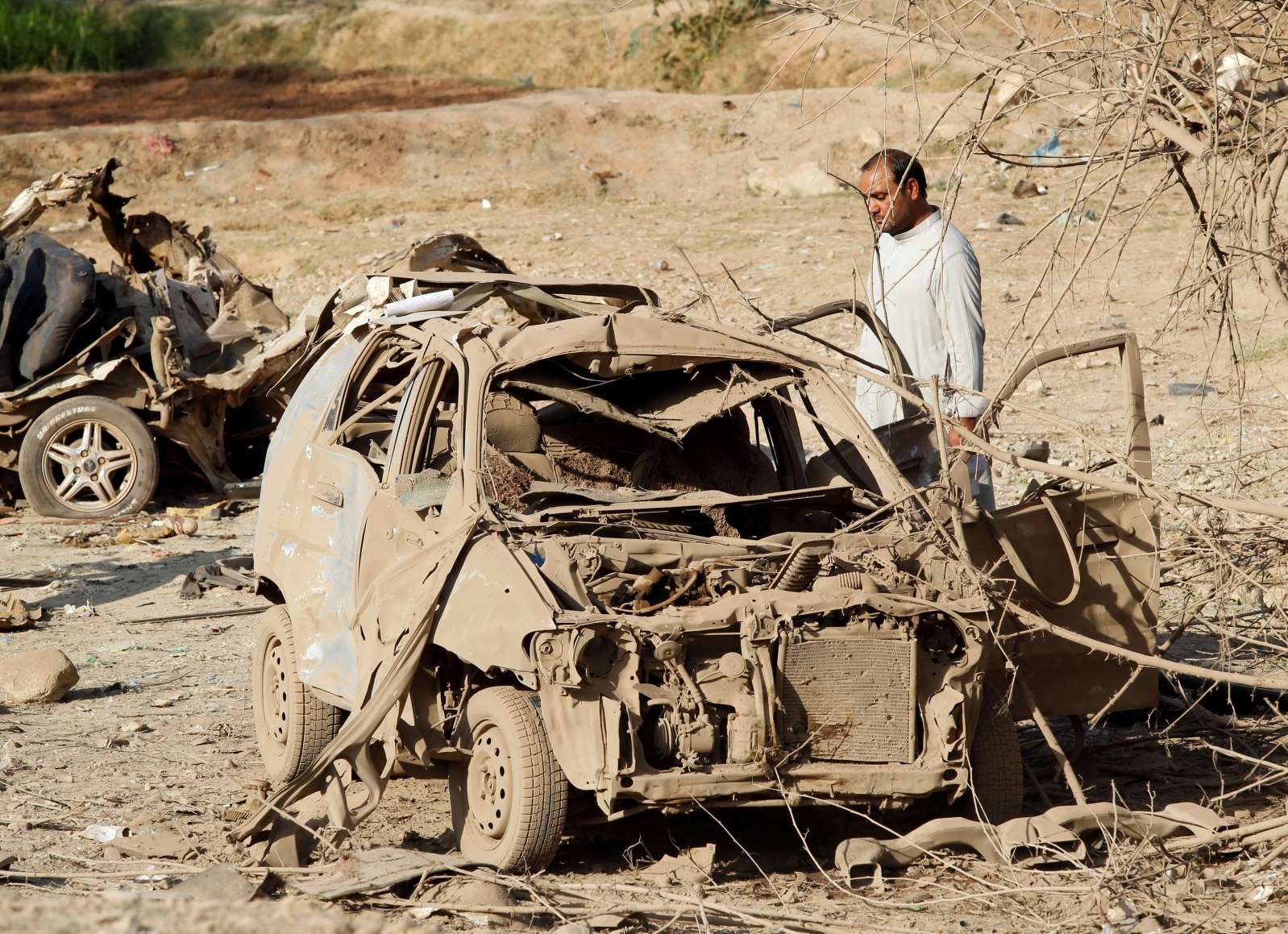 an afghan man inspects the wreckage of a car at the site of a truck bomb blast in ghani khel district of nangarhar province afghanistan reuters