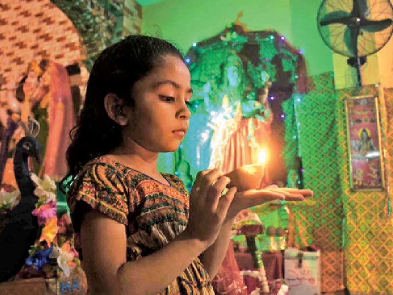 a child holds an earthen lamp as she celebrates diwali at a temple hindus across the globe make merry at the festival of lights decorating their homes and setting off fireworks photo inp