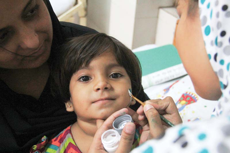 a volunteer of the pakistan helping hands paints a flag on the face of a child admitted to nich on sunday photo ayesha mir express