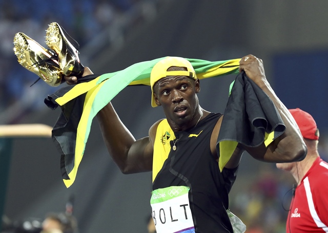 usain bolt carries his shoes in his hands after winning the gold medal photo reuters