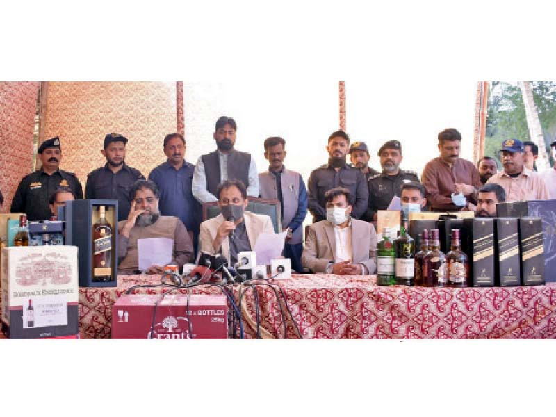 customs officials show bottled of smuggled liquor seized from two houses in the dha photo express