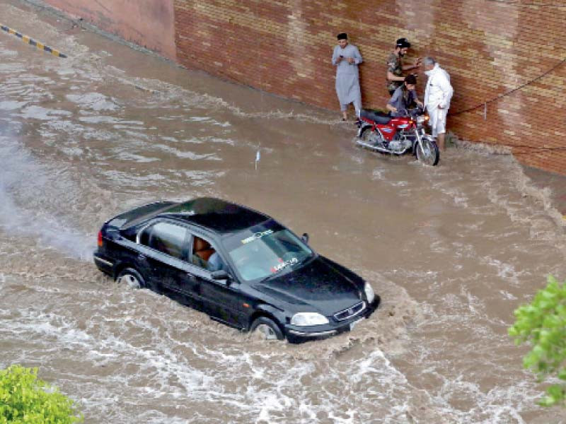 motorists and commuters struggle on a swamped road after peshawar received a heavy downpour on thursday photo ppi