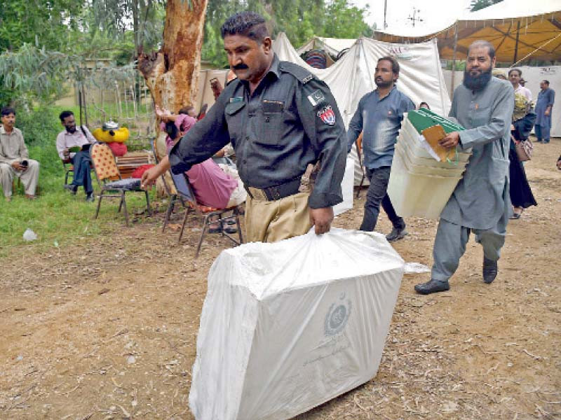 a police officer and polling agents carry electoral material for na 245 by elections in karachi photo online
