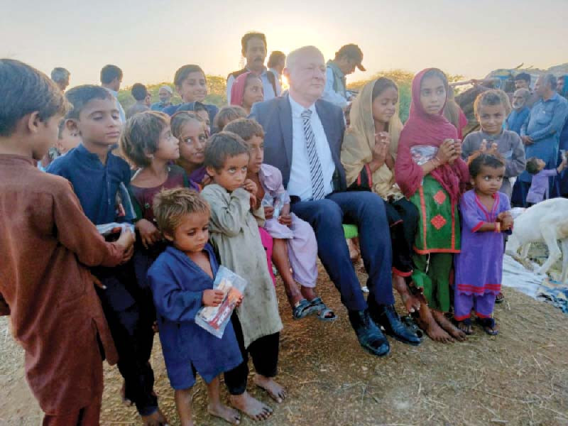 dr rudiger lotz the german consul general in karachi shares a light moment with the flood hit children during his visit to a relief camp in tando jan mohammad on tuesday photo express
