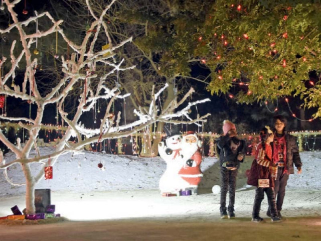 children belonging to the christian community stand near roadside decorations during a christmas ceremony in sector f 6 in the federal capital photo online